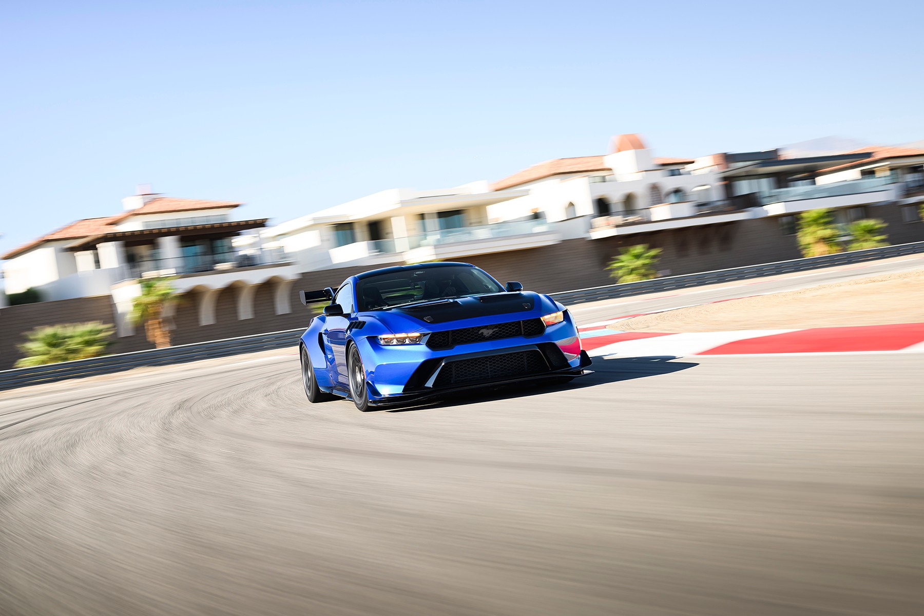 A blue Ford Mustang GTD cornering at speed on a circuit