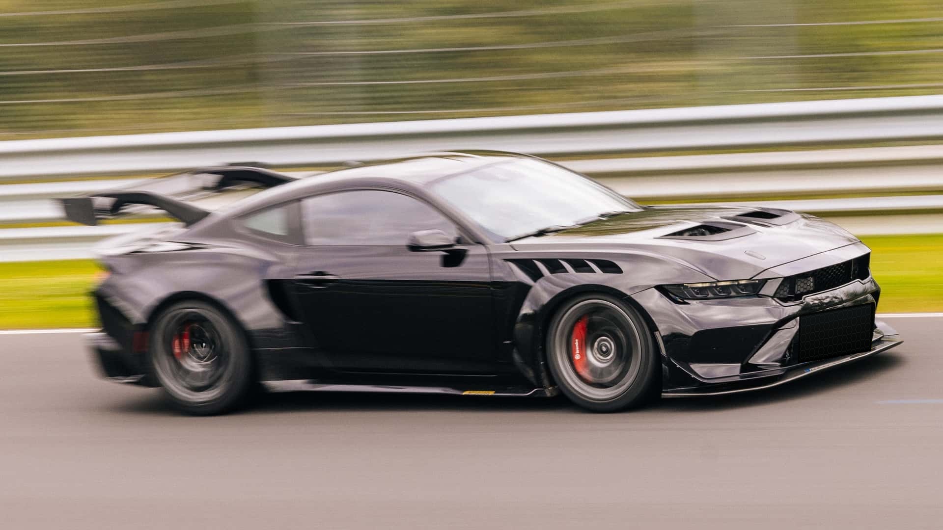 A glossy black Ford Mustang GTD captured in a lateral high-speed pan at the Nürburgring